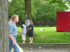 zwei kinder bleiben vor dem baum mit dem pissoir stehen und wundern sich