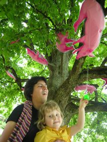 tatsuo und kaspar unter der baum der voll ist mit easyart schweinen. Kaspar zupft freudig an einem herabhängendem "tiertonmaschinchen"